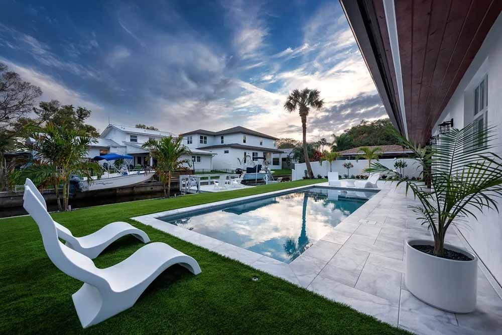 There is a large swimming pool in the backyard of a house.