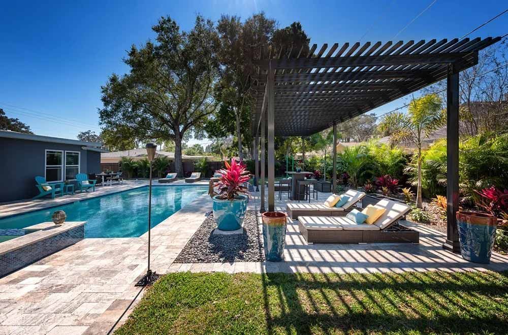 There is a large swimming pool in the backyard with a pergola.