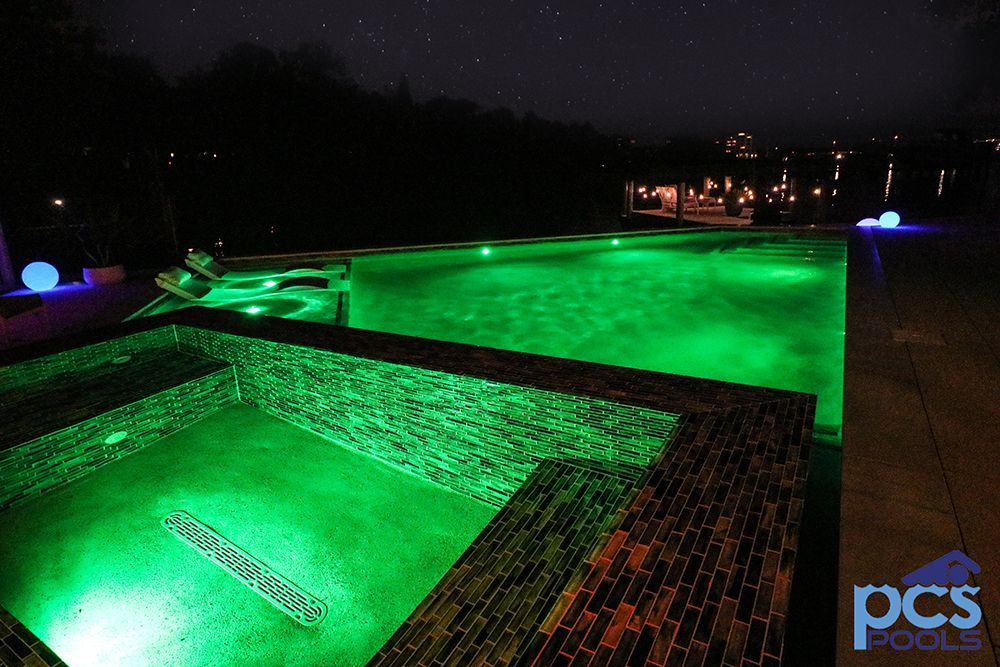 A swimming pool is lit up with green lights at night