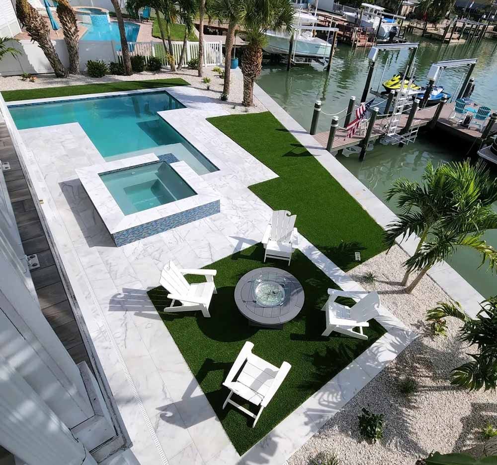 An aerial view of a swimming pool with chairs and a fire pit