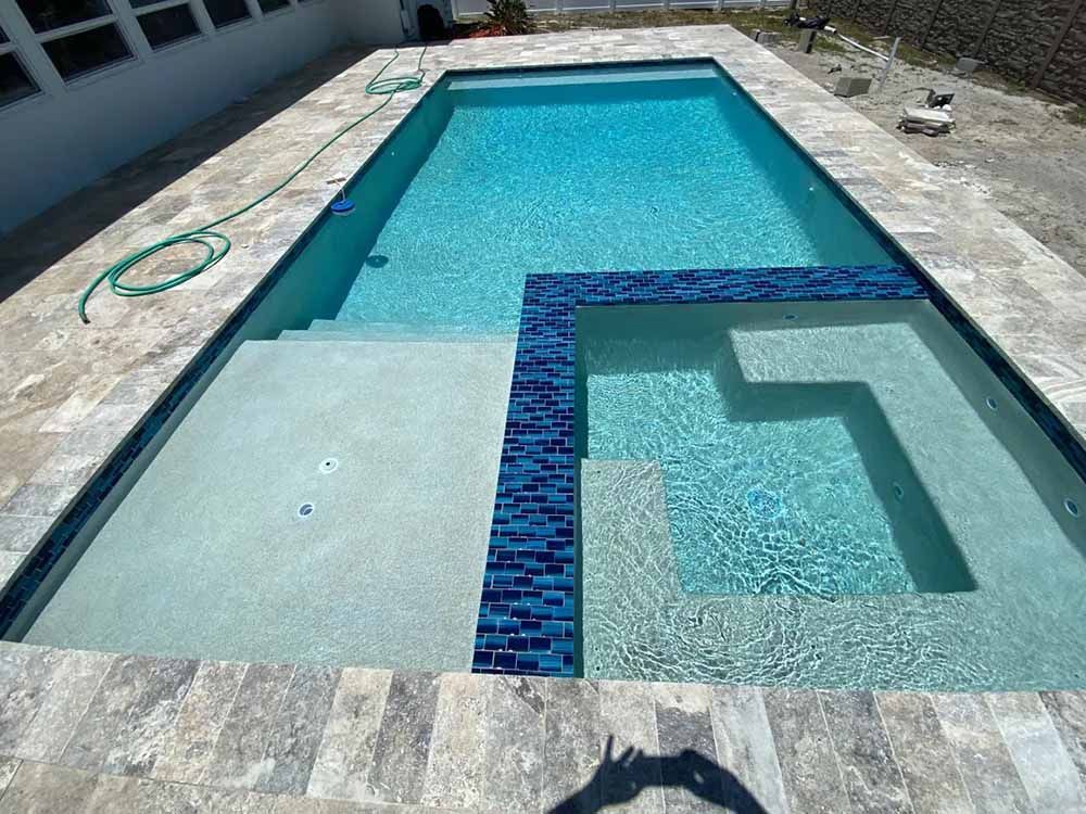 A large swimming pool with stairs and a hose on the side of it.