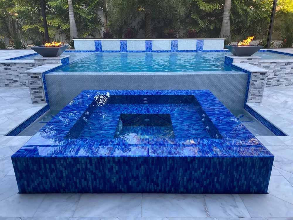 A large swimming pool with a hot tub in the middle of it.