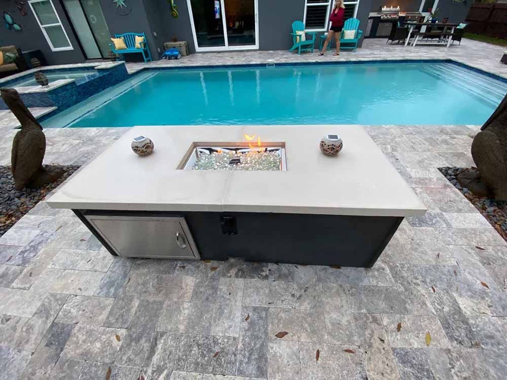 A fire pit is sitting next to a large swimming pool.