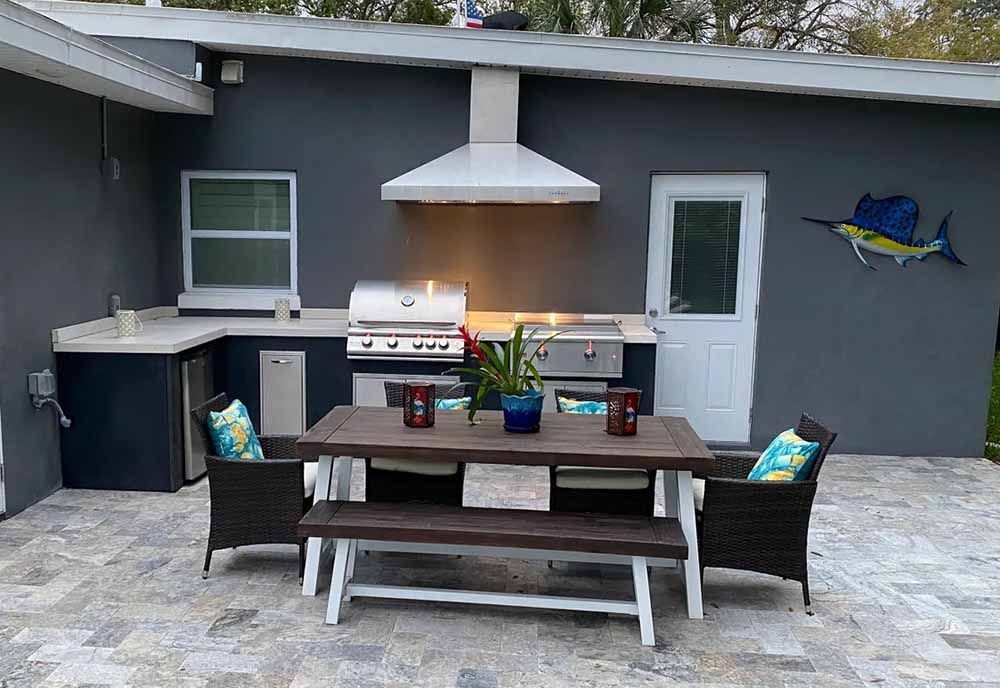 A patio with a table , chairs and a grill.