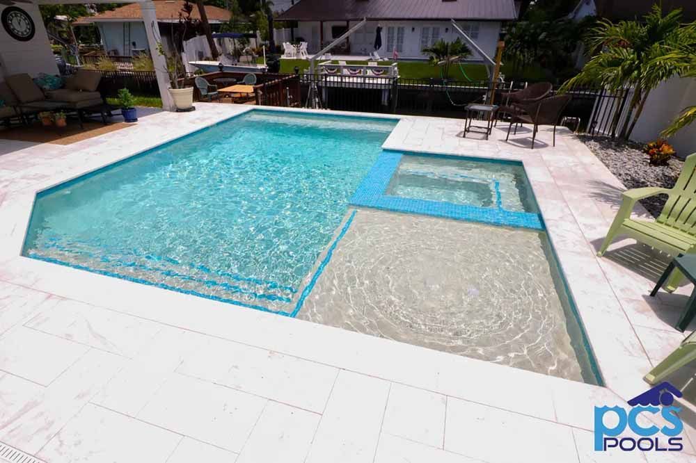A large swimming pool is sitting on top of a tiled patio next to a house.