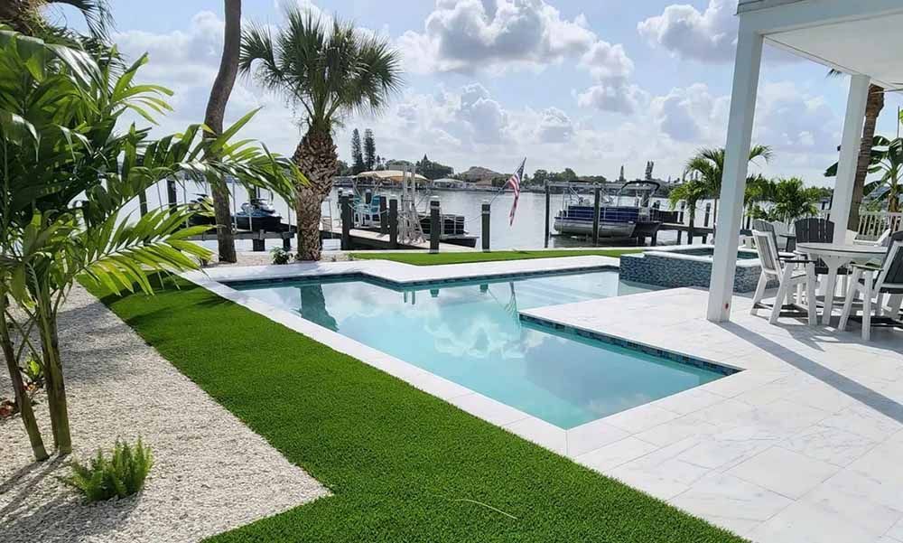 There is a large swimming pool in the backyard of a house.