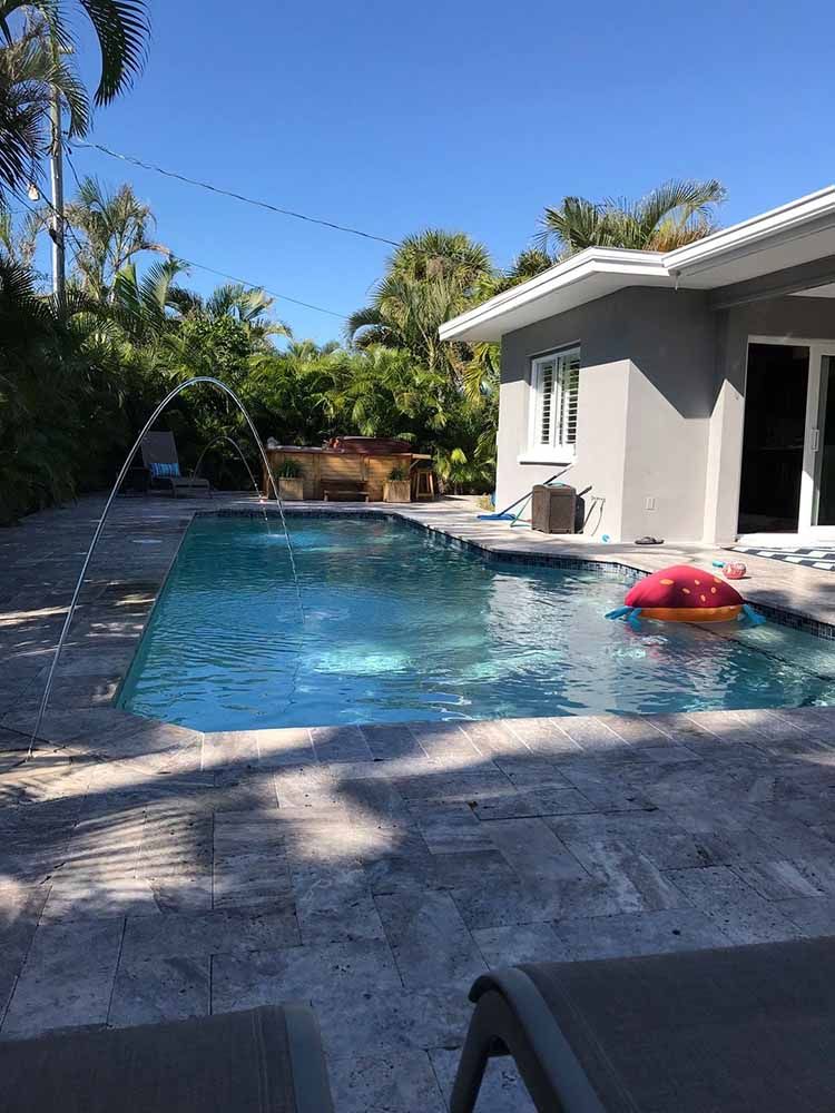 There is a large swimming pool in the backyard of a house.