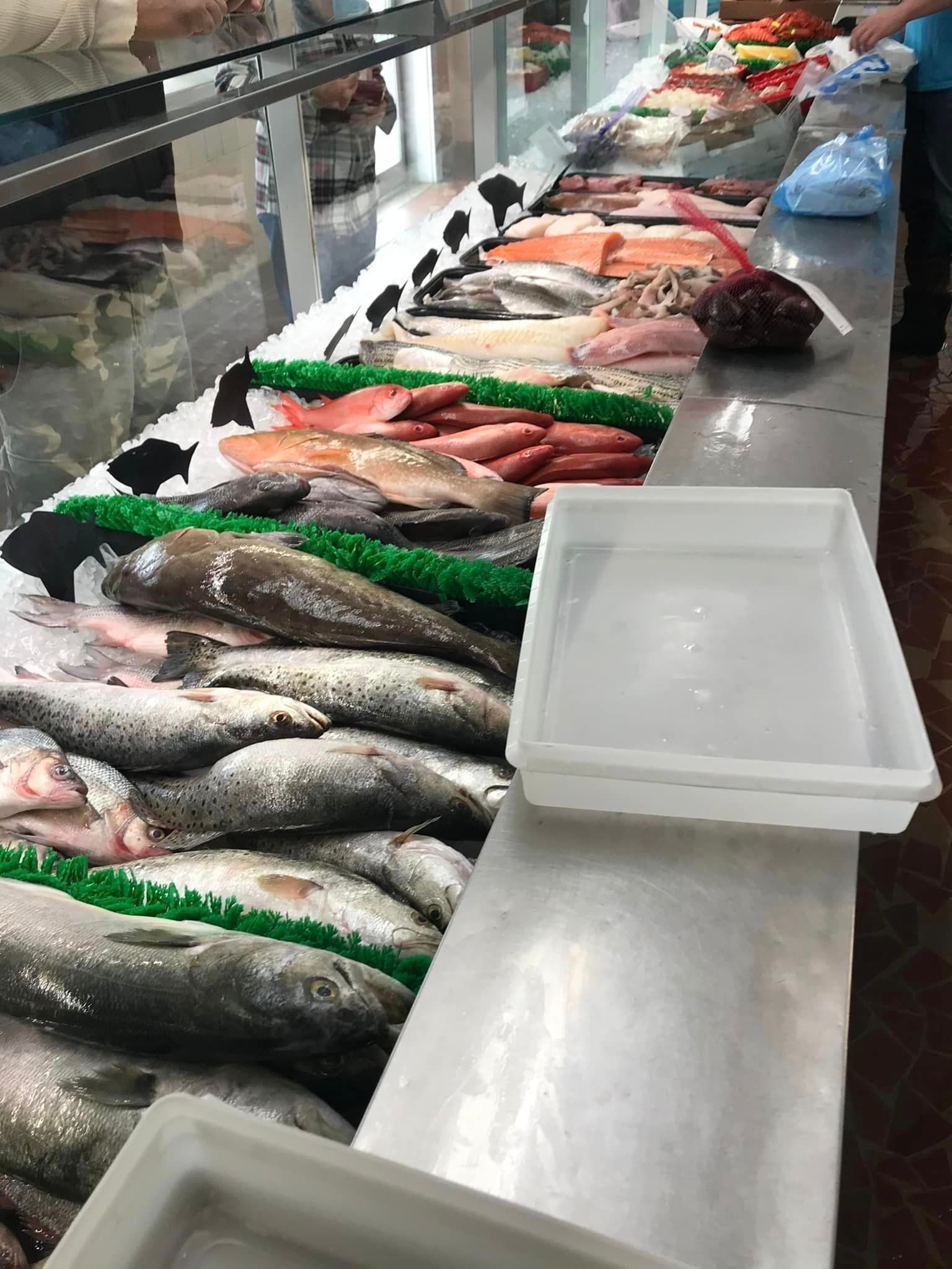 A high-angle view of a fish market display case filled with various fresh whole fish arranged on a bed of crushed ice.
