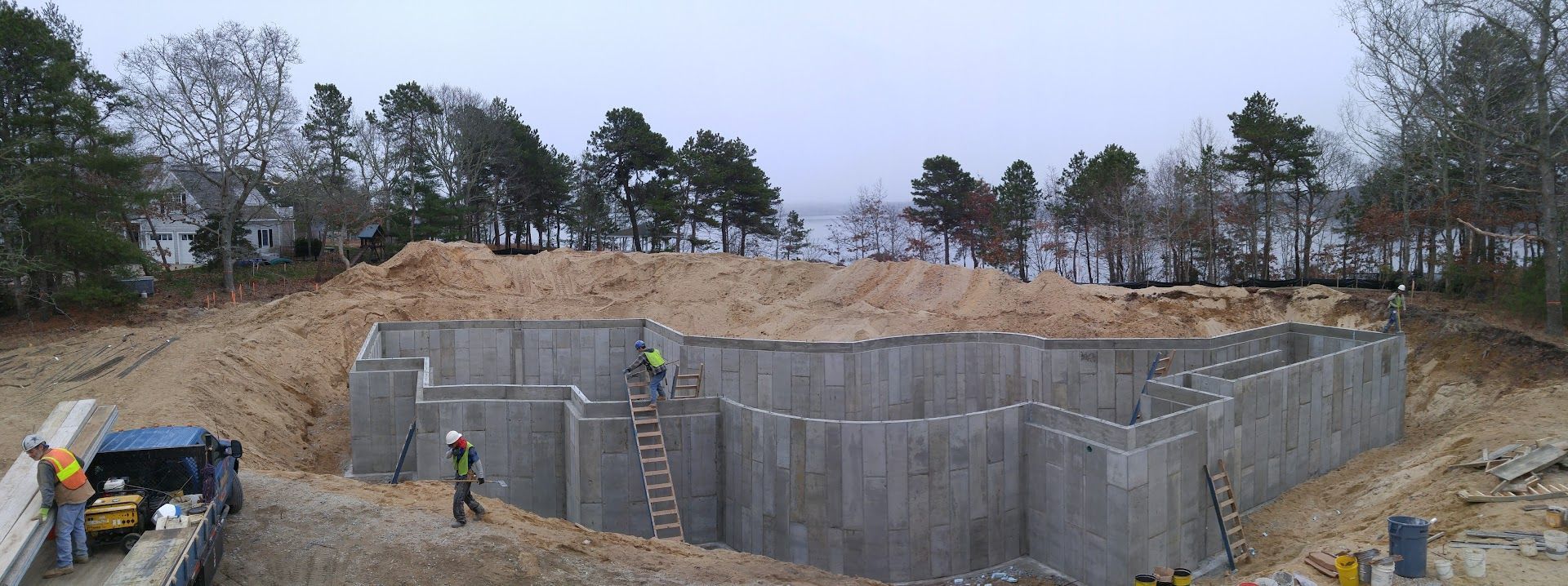 A large concrete wall is being built in the middle of a dirt field.