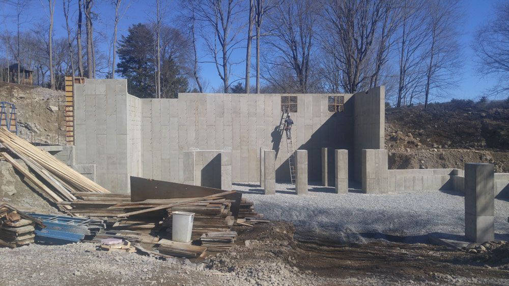 A large concrete wall is being built in the middle of a dirt field.
