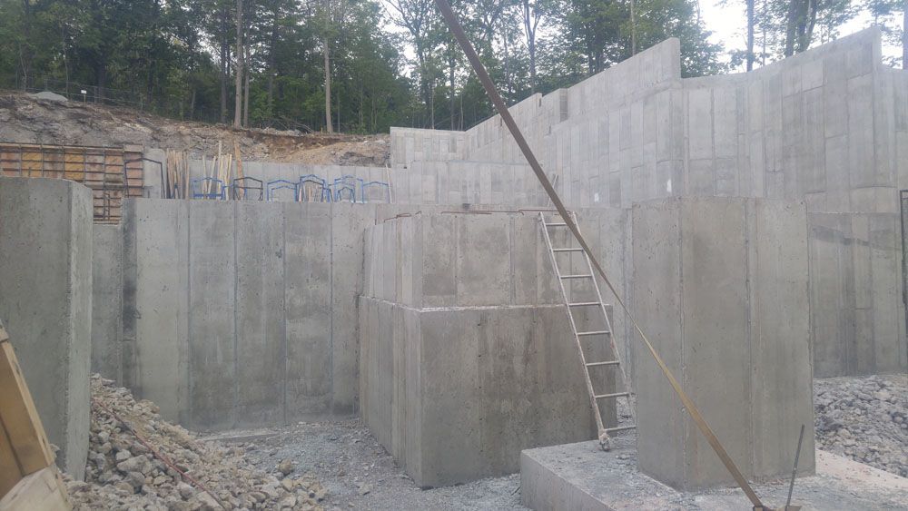 A large concrete wall is being built with a ladder.