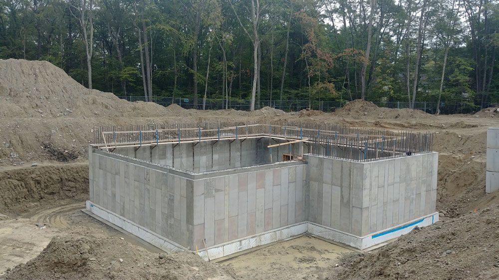 A large concrete foundation is being built in a dirt field.