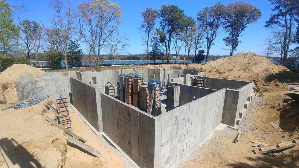 A large concrete basement is being built in the middle of a dirt field.
