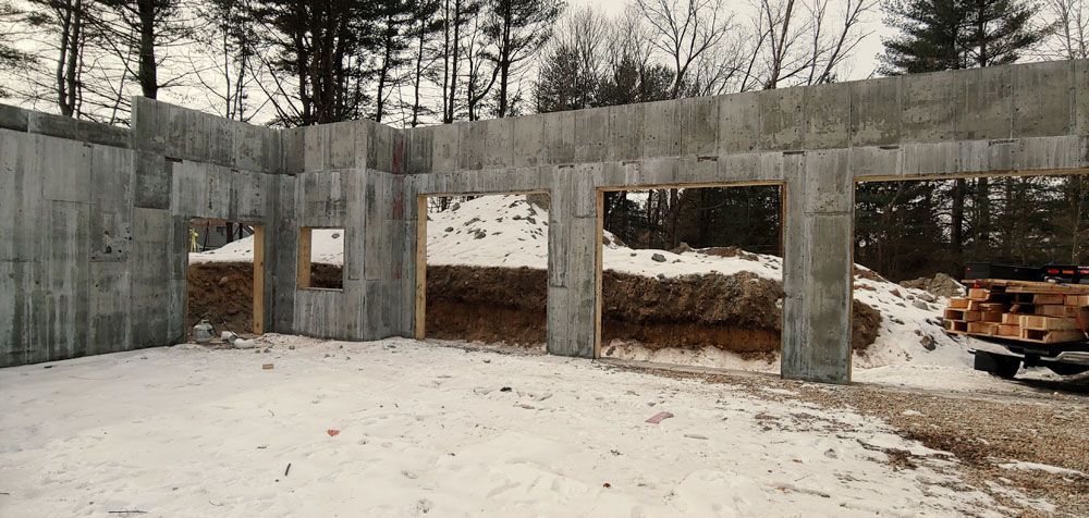 A large concrete wall is being built in the snow.