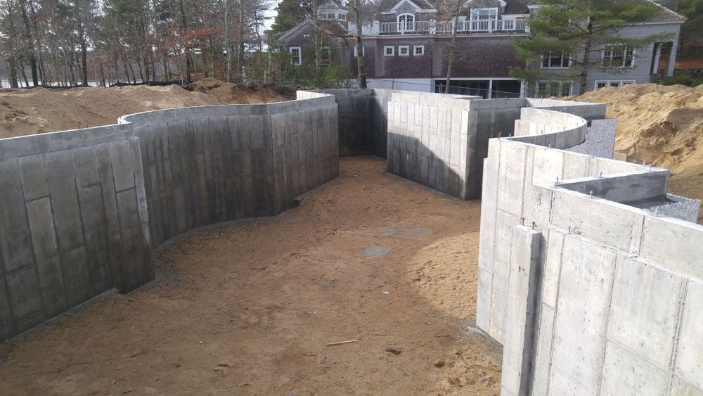 A large concrete wall is being built in front of a house.