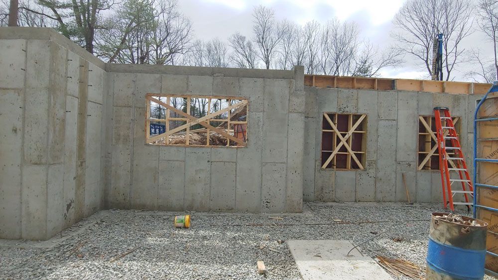A concrete wall with a ladder in the background is being built.