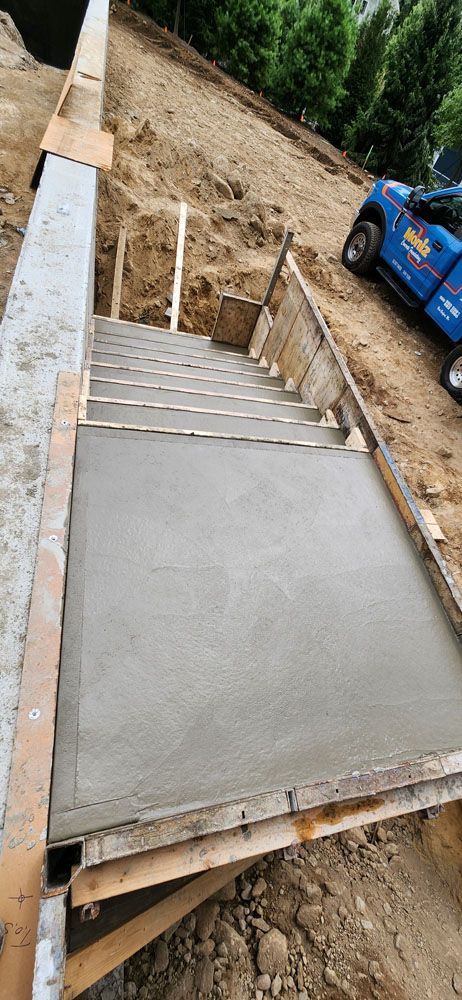 A blue truck is parked next to a set of concrete stairs being built.