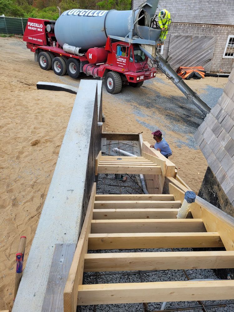 A concrete mixer truck is pouring concrete into a wooden staircase.