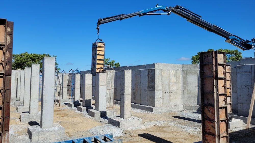 A crane is lifting a concrete pillar in a construction site.
