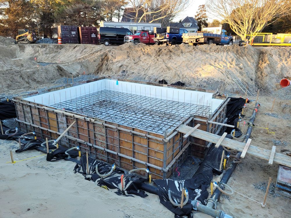 A large concrete foundation is being built in a dirt field.