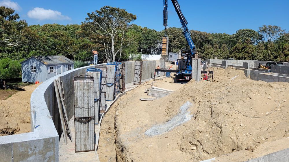 A large concrete wall is being built with a crane in the background.