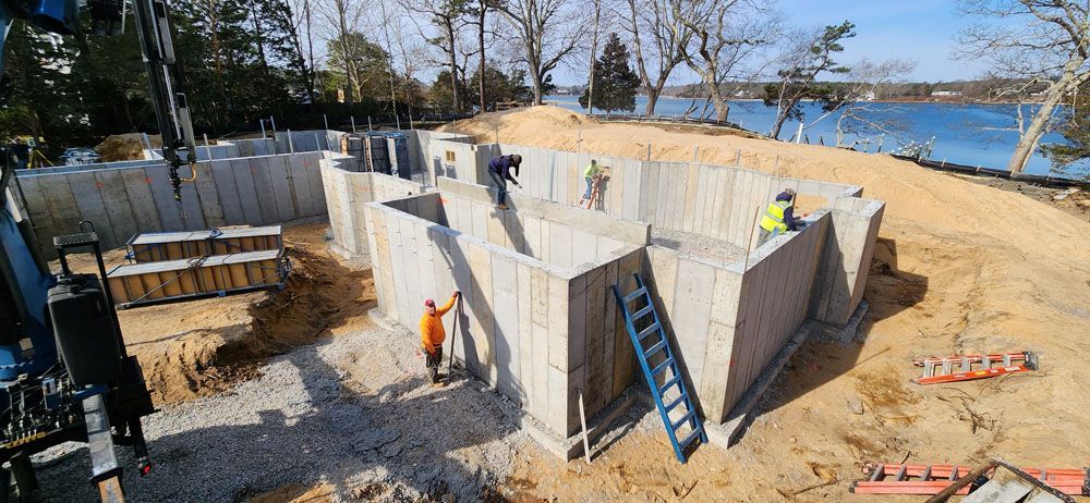 A group of construction workers are working on a large concrete wall.
