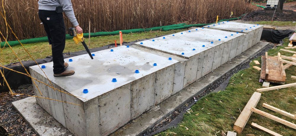 A man is standing on top of a large concrete block holding a saw.
