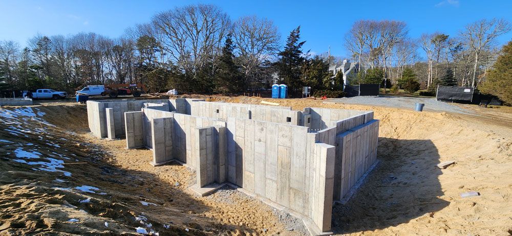 A large concrete wall is sitting in the middle of a dirt field.