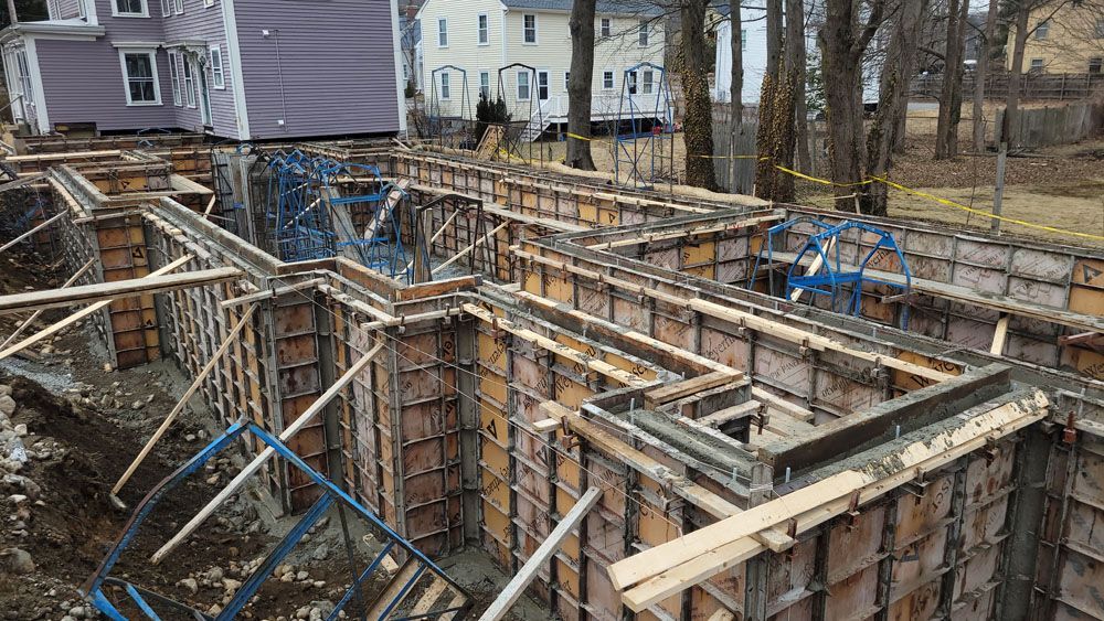 A large concrete wall is being built in front of a house.