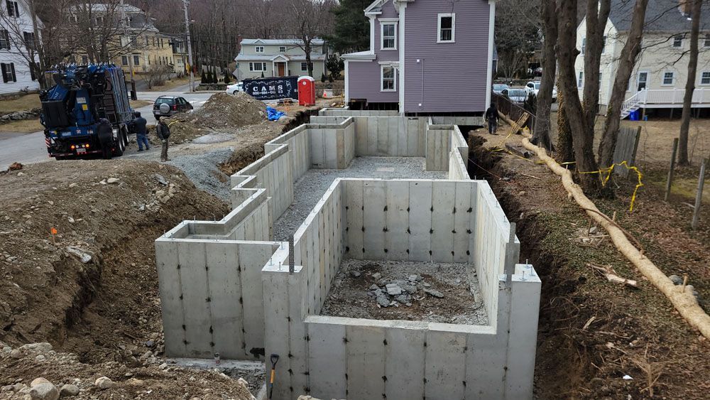 A purple house is being built next to a large concrete wall.