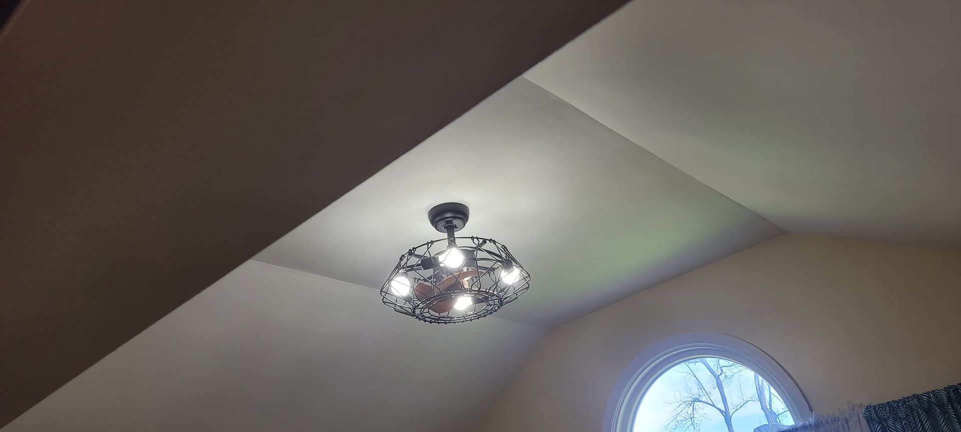 Ceiling with a chandelier and an arched window.