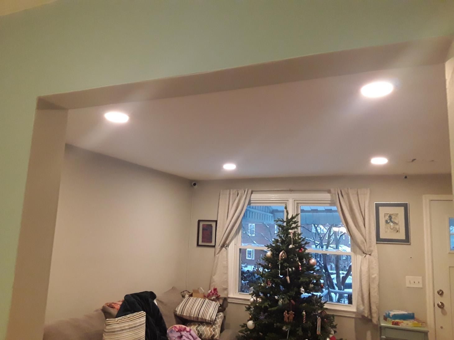 Living room with recessed lighting, Christmas tree, window with curtains, and doorway.