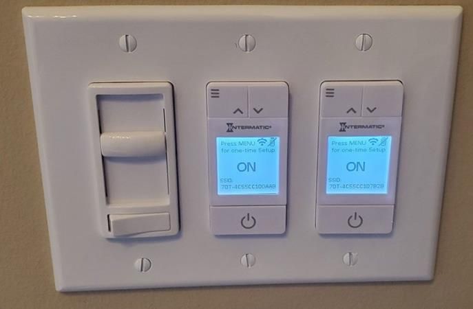 White light switch plate with a dimmer and two smart switches, each displaying