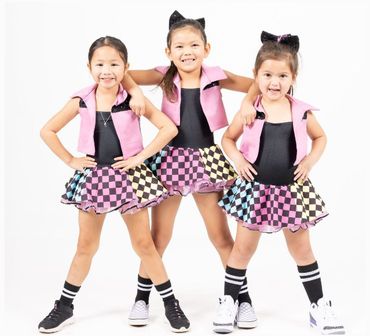 three little girls wearing pink dancewear