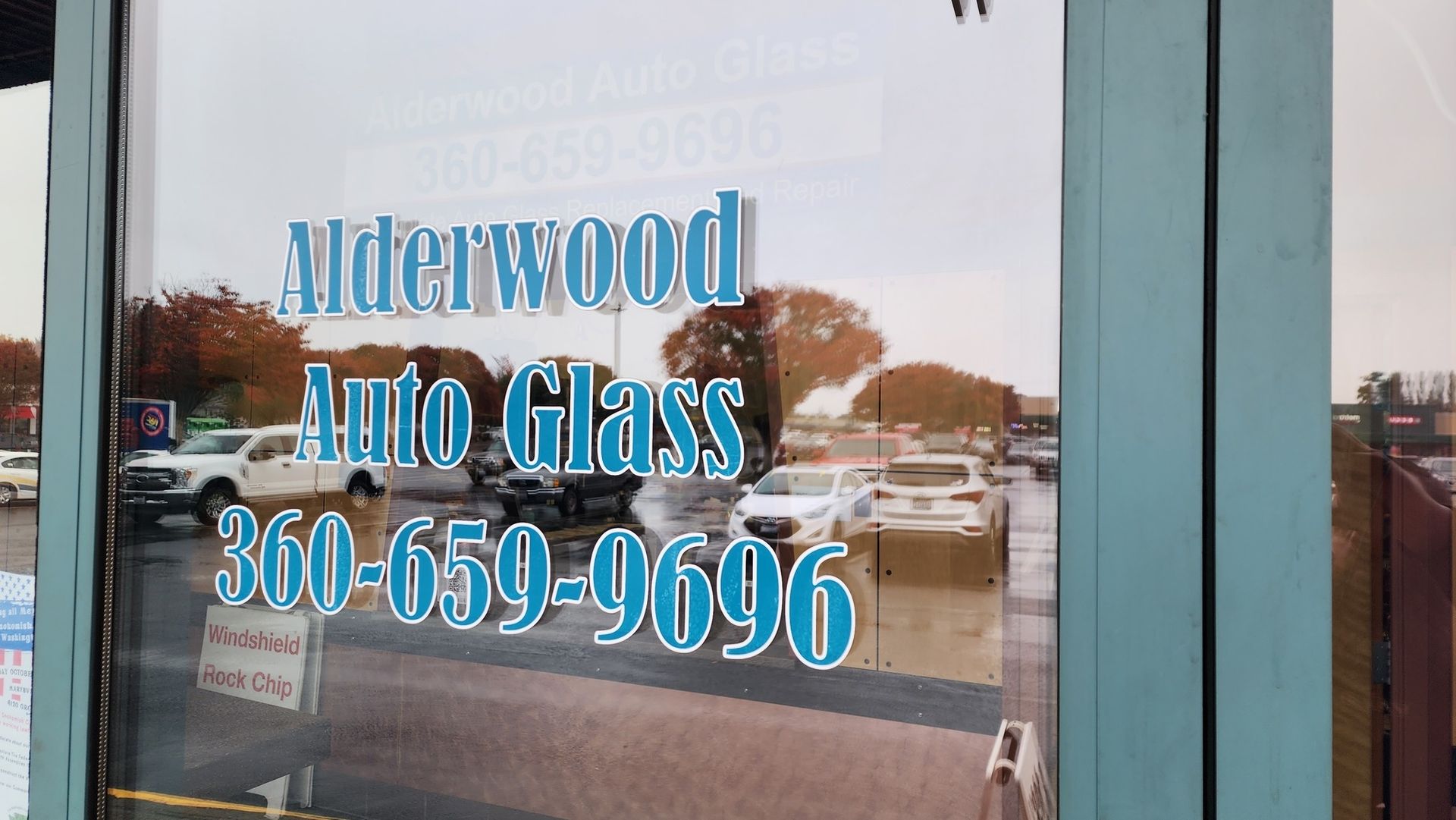Alderwood Auto Glass business front with blue lettering and phone number 360-659-9696 on glass door.