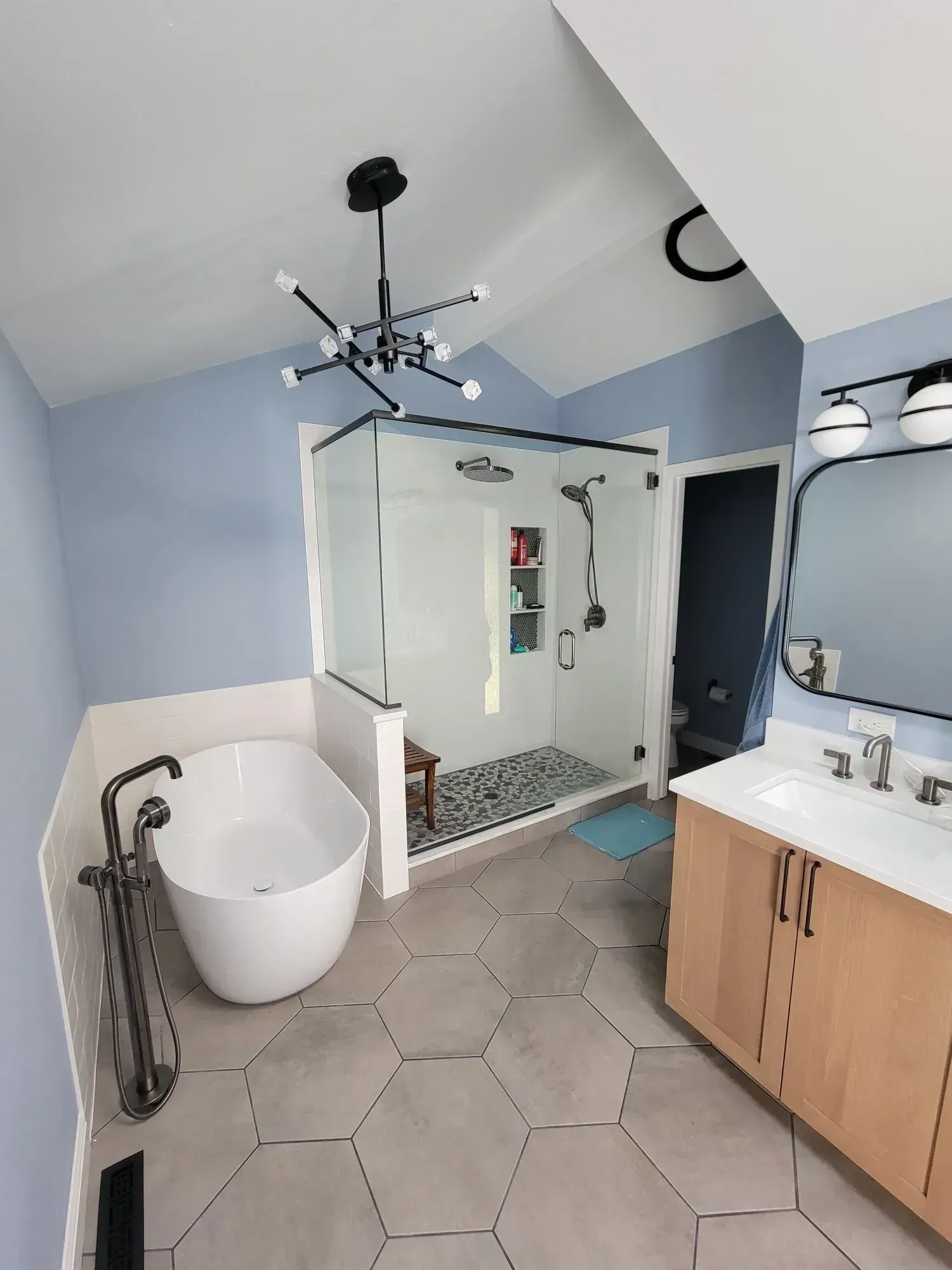 A bathroom with a tub , sink , mirror and shower.