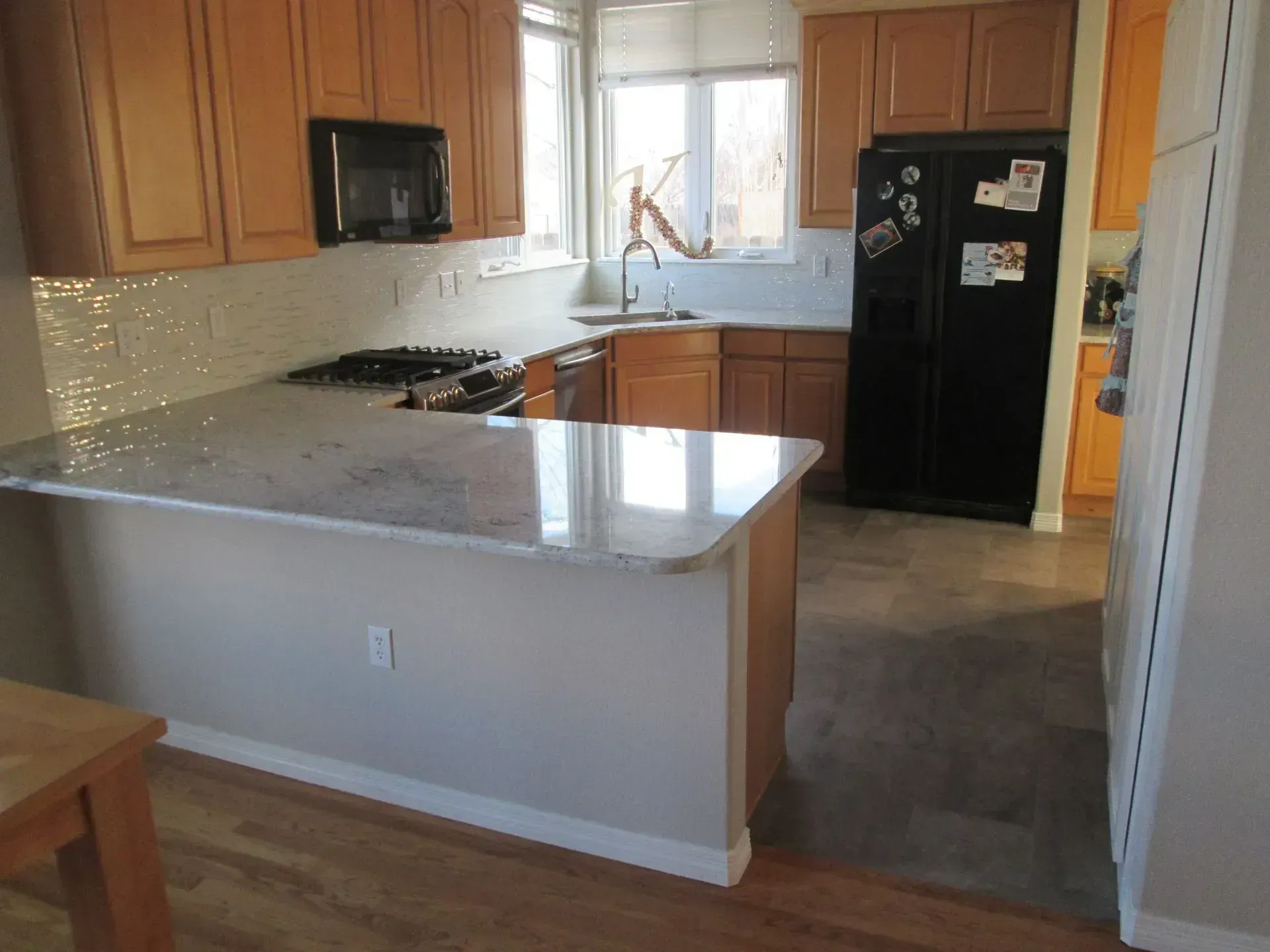 A kitchen with wooden cabinets and a black refrigerator