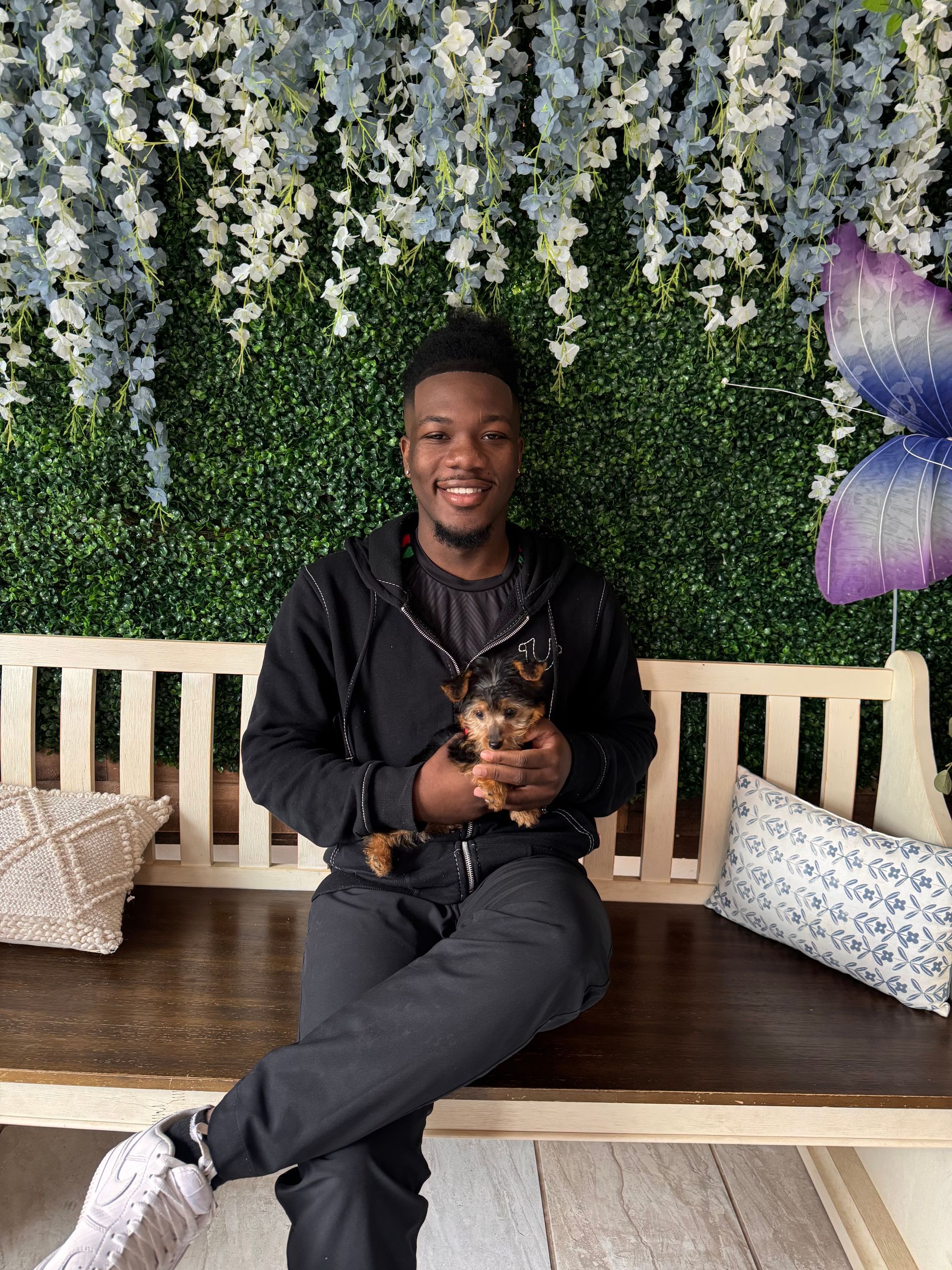 Small fluffy puppy in a floral wooden crate with white flowers and a hello sunshine sign