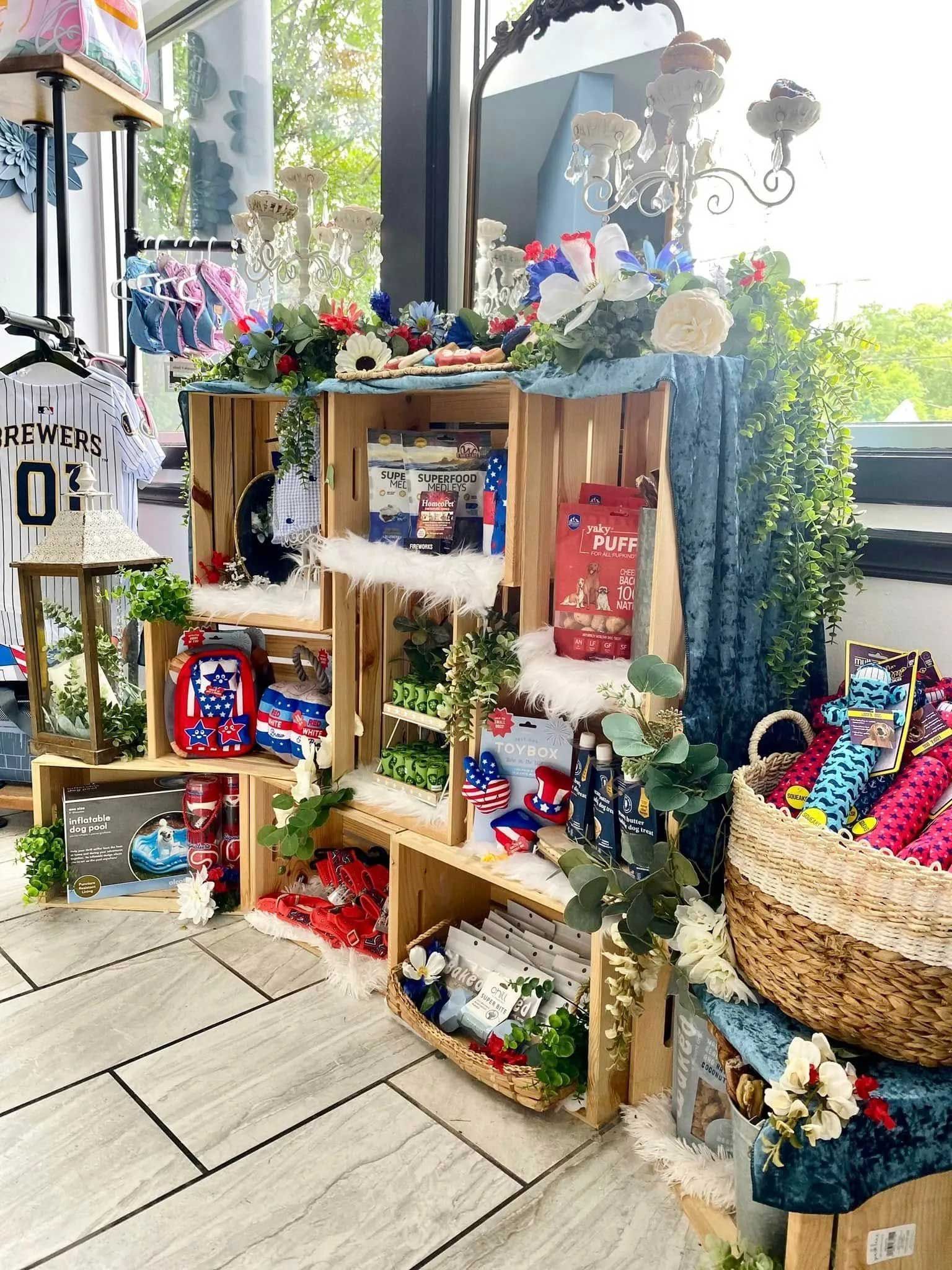 A retail display made of stacked wooden crates filled with red, white, and blue decor and floral accents, near a basket.