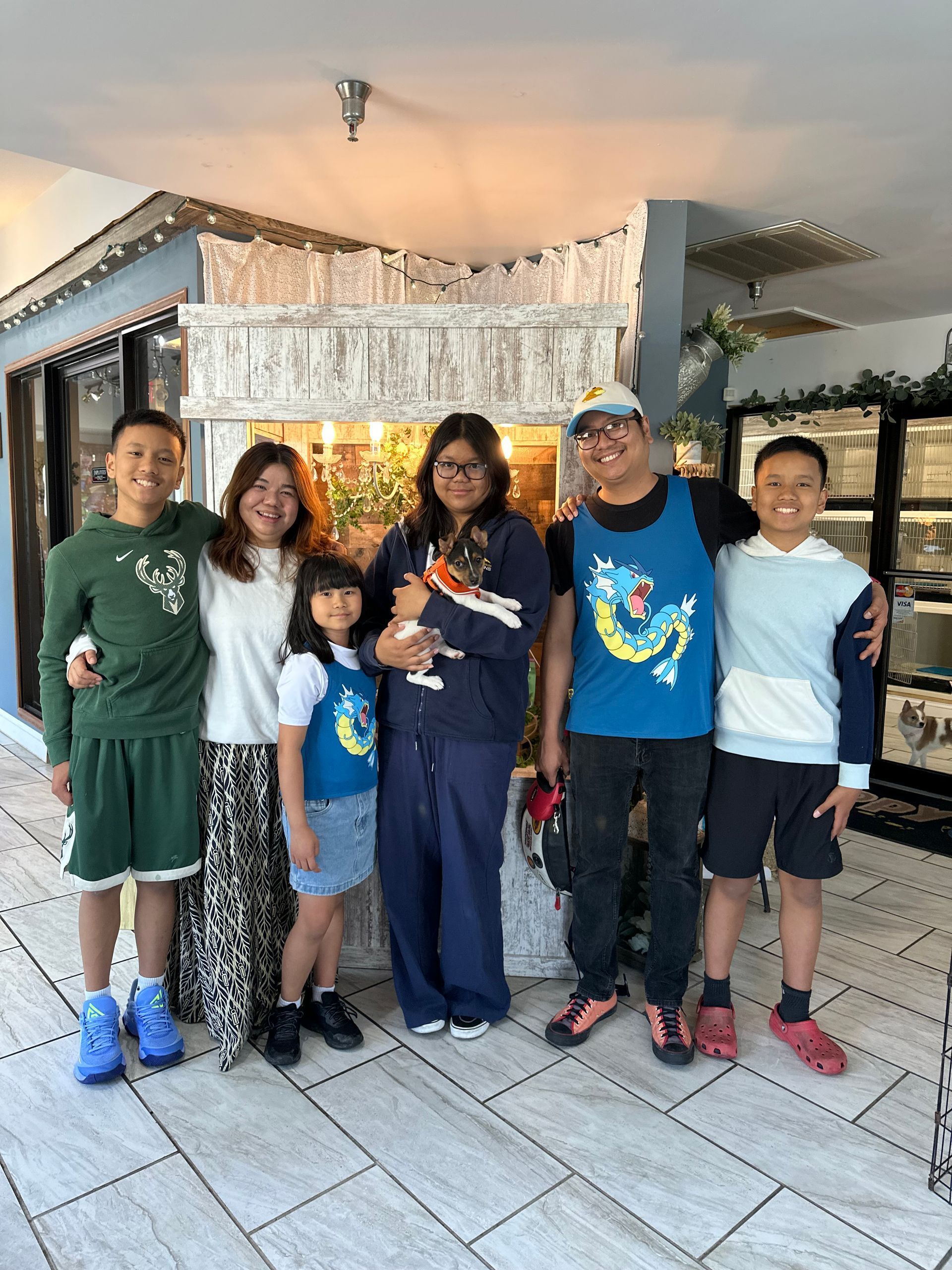 Six people posing together in front of a decorated house entrance, smiling at the camera.