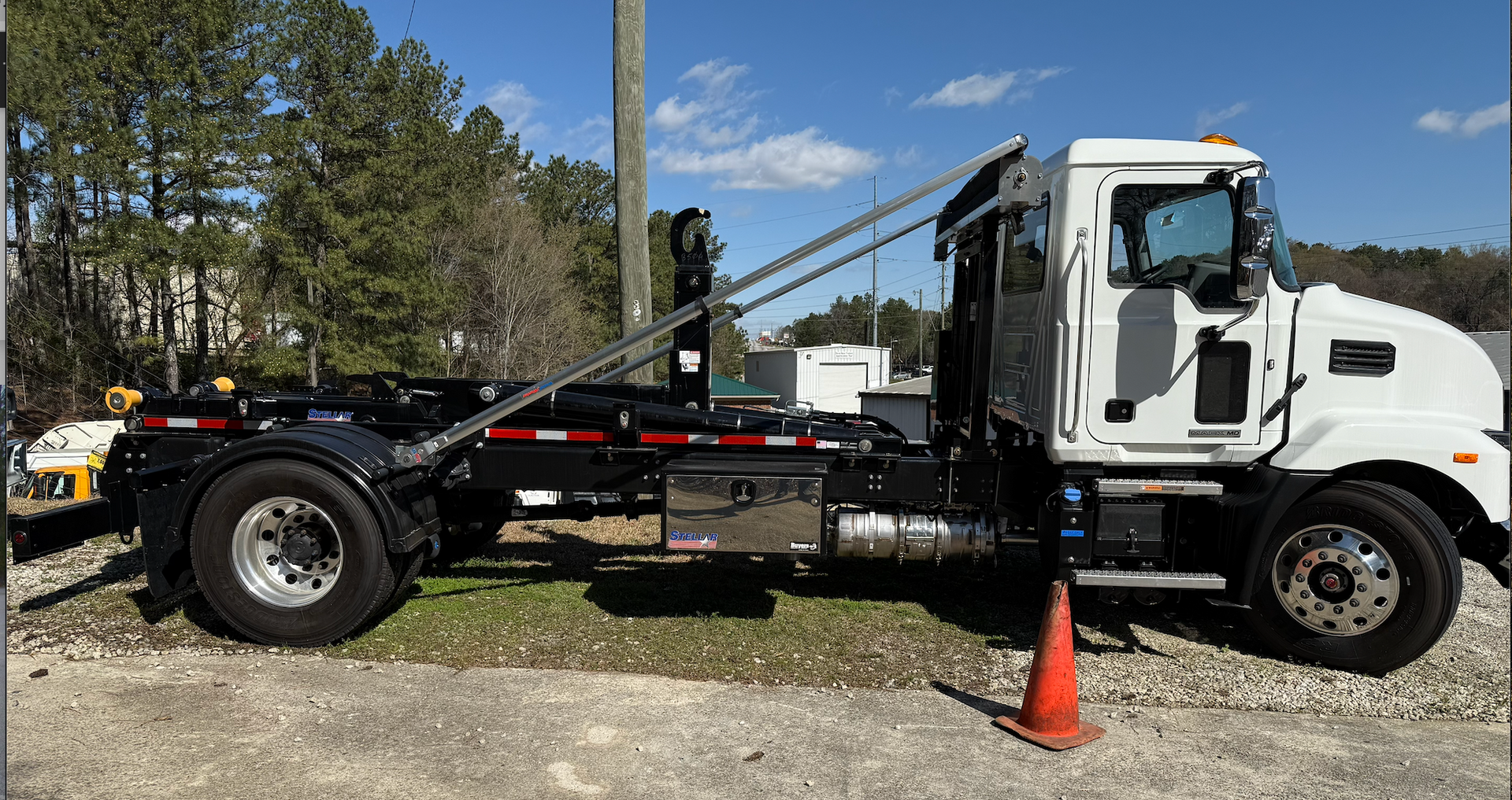 A white mack truck is parked in a gravel lot.