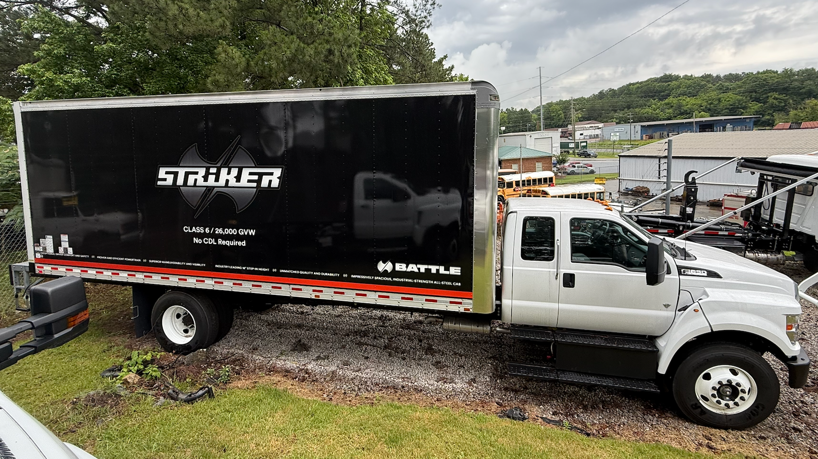 A white truck with a flatbed trailer is parked in a parking lot.