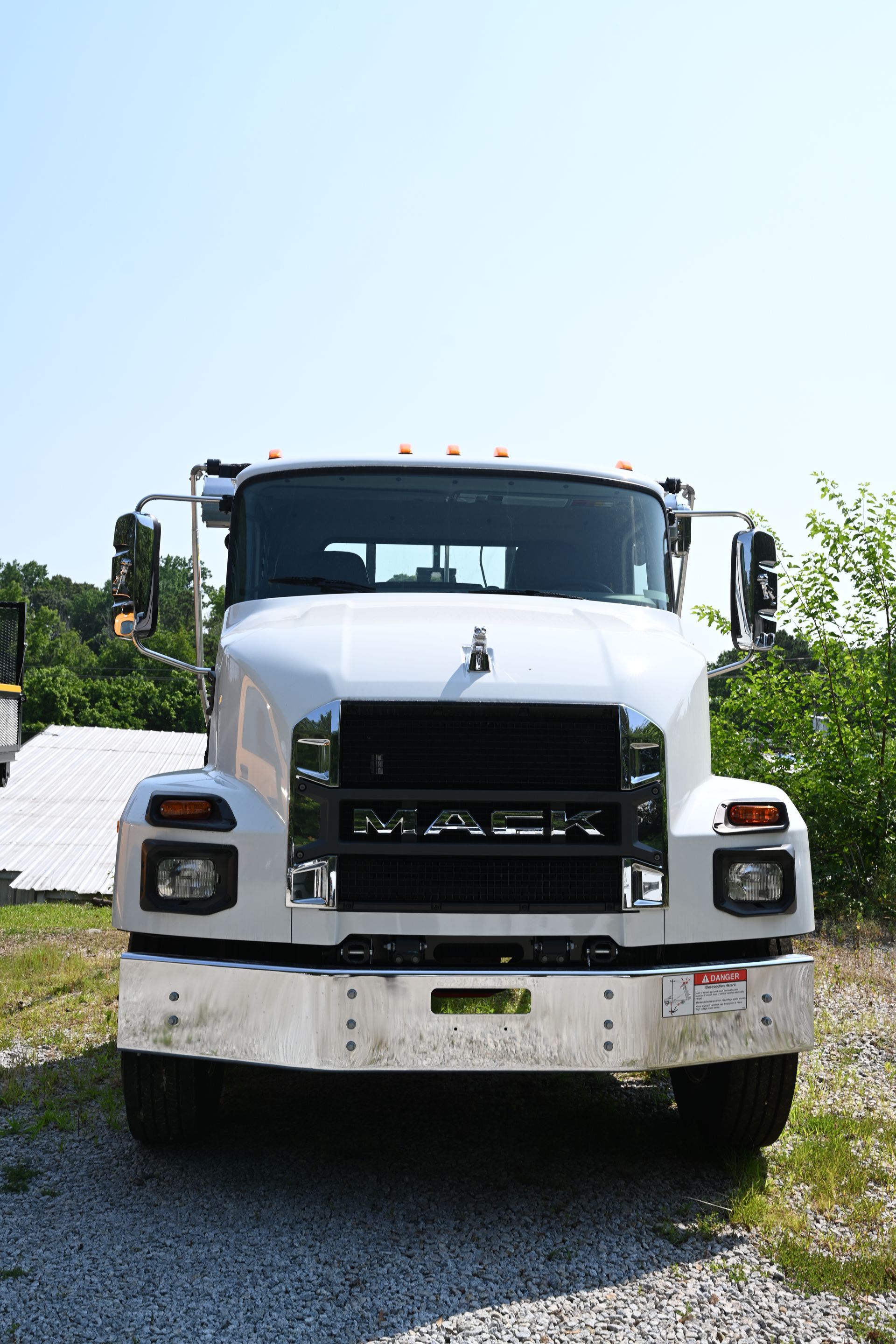 A white truck is parked in a gravel lot.