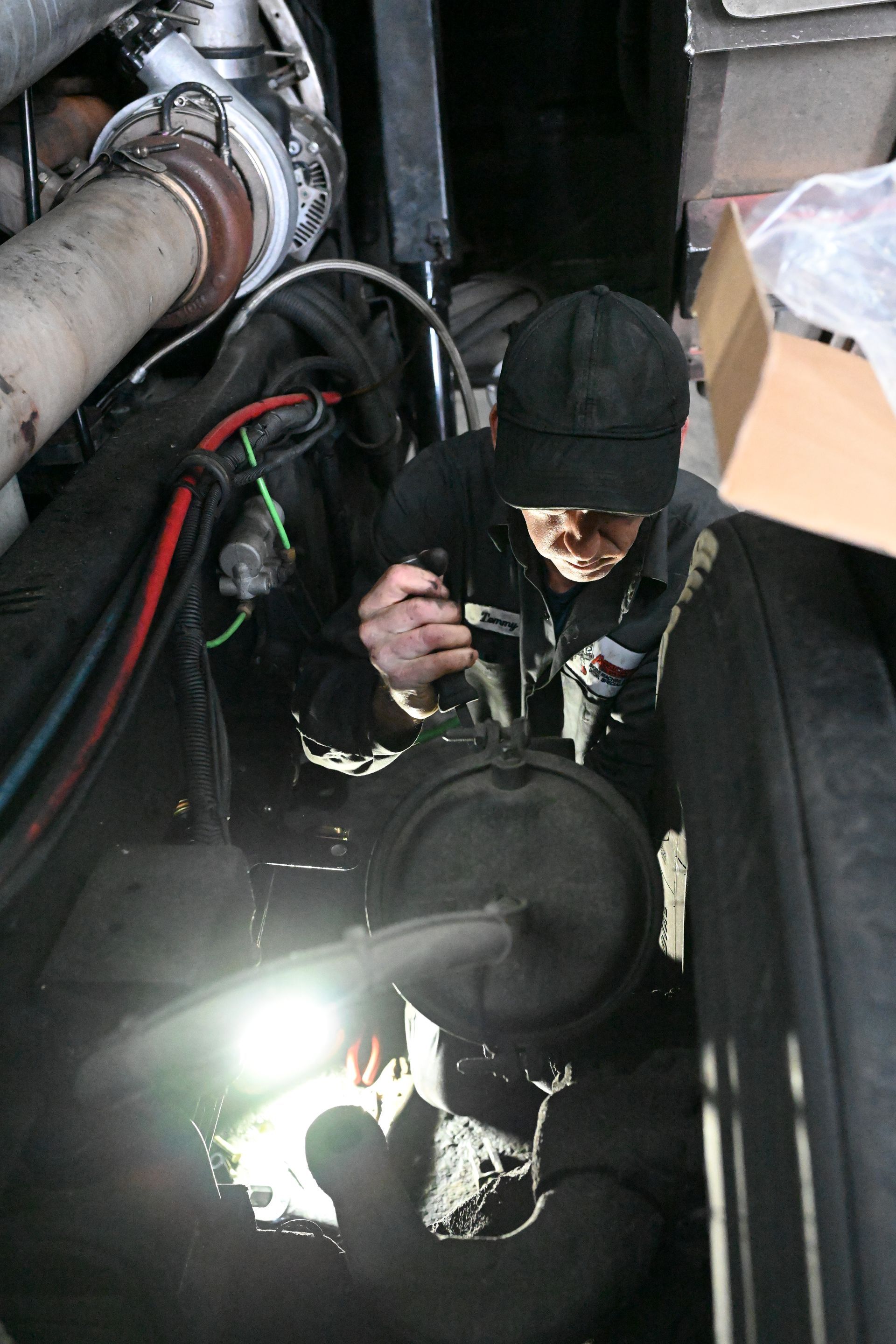 A man in a black hat is working on a machine
