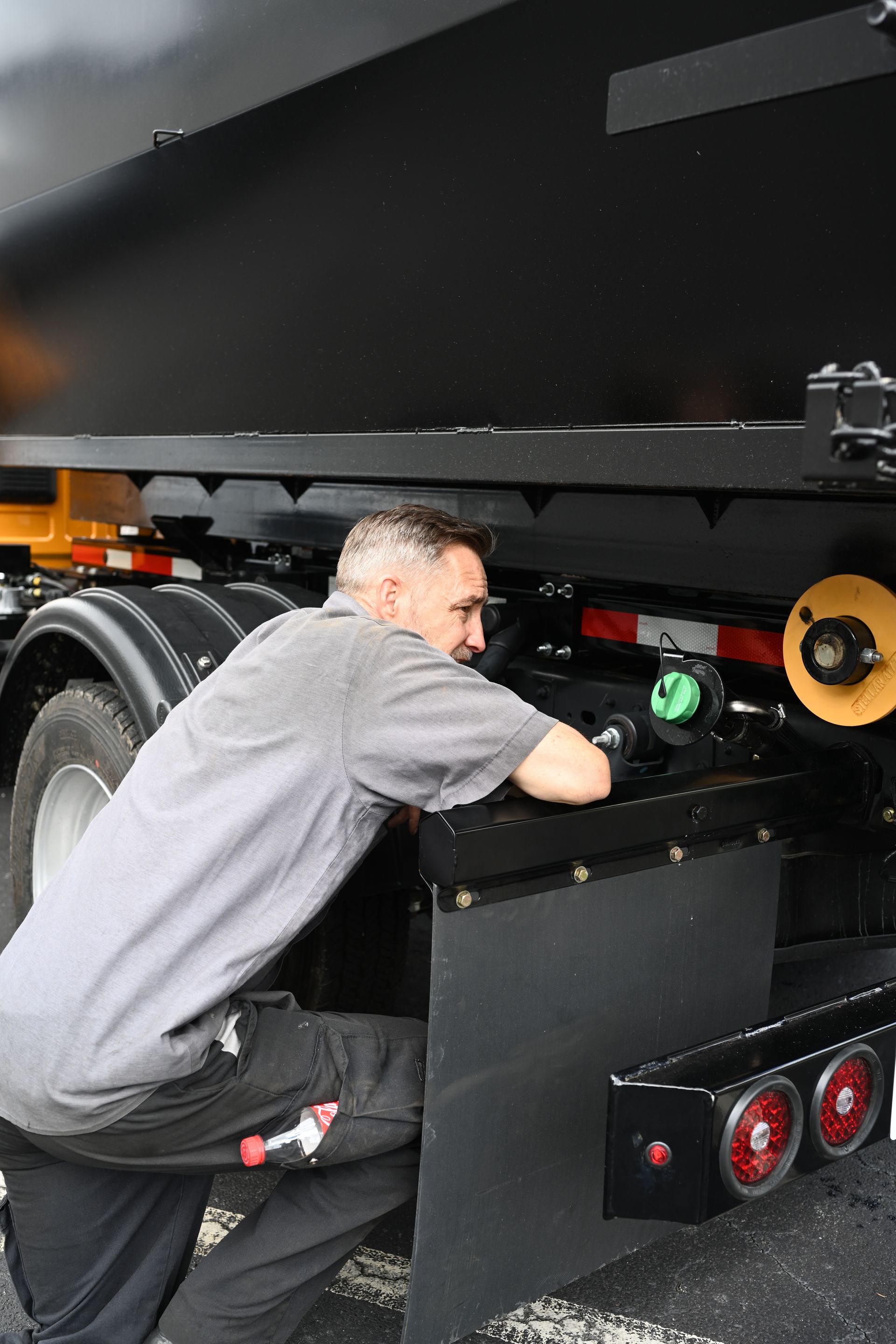 A man is working on the back of a dump truck.