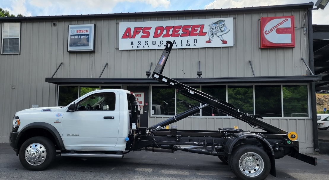A white dump truck is parked in front of a building.