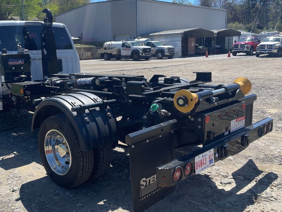 A dump truck is parked in a parking lot next to a van.