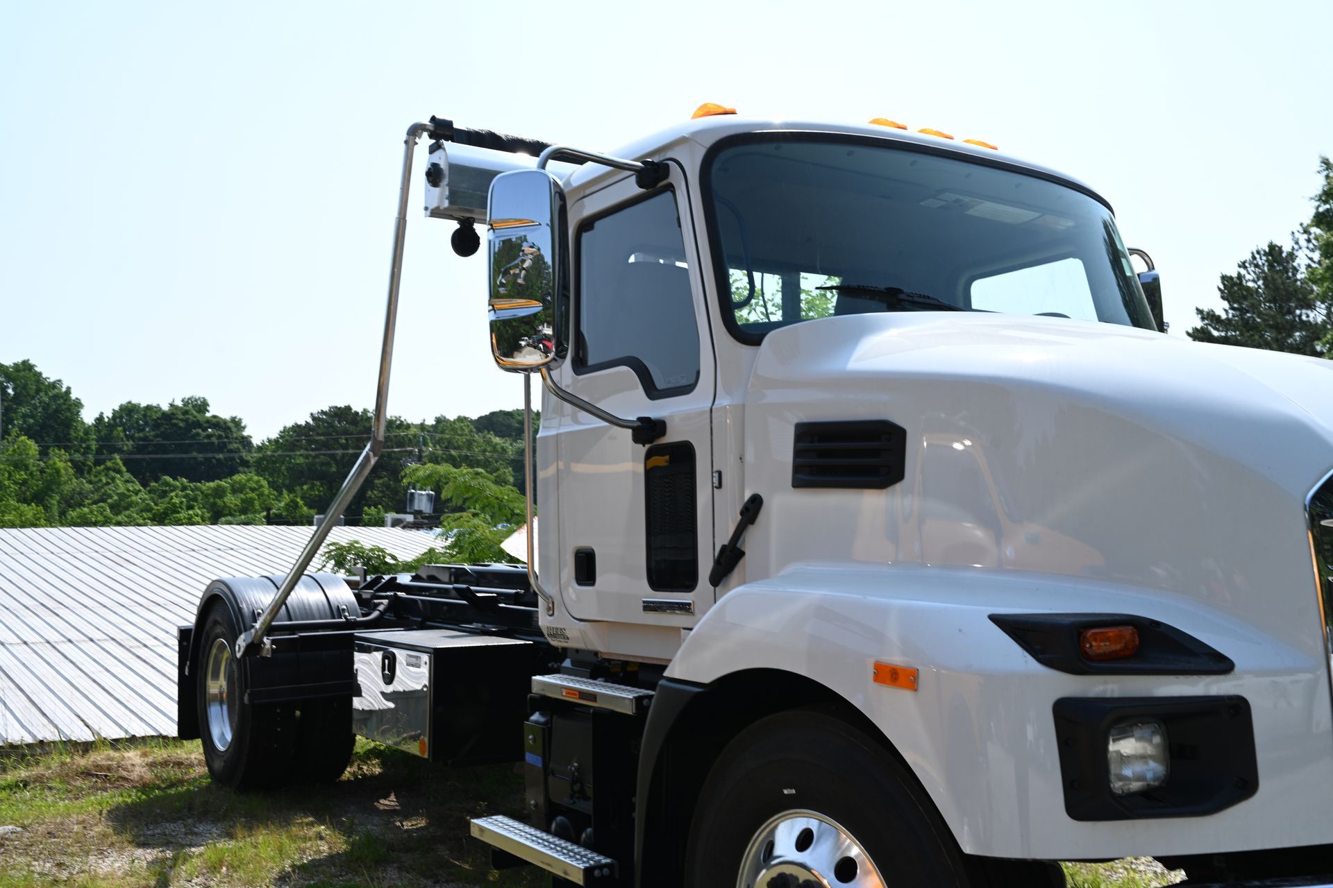 A white dump truck is parked in the grass in front of a building.