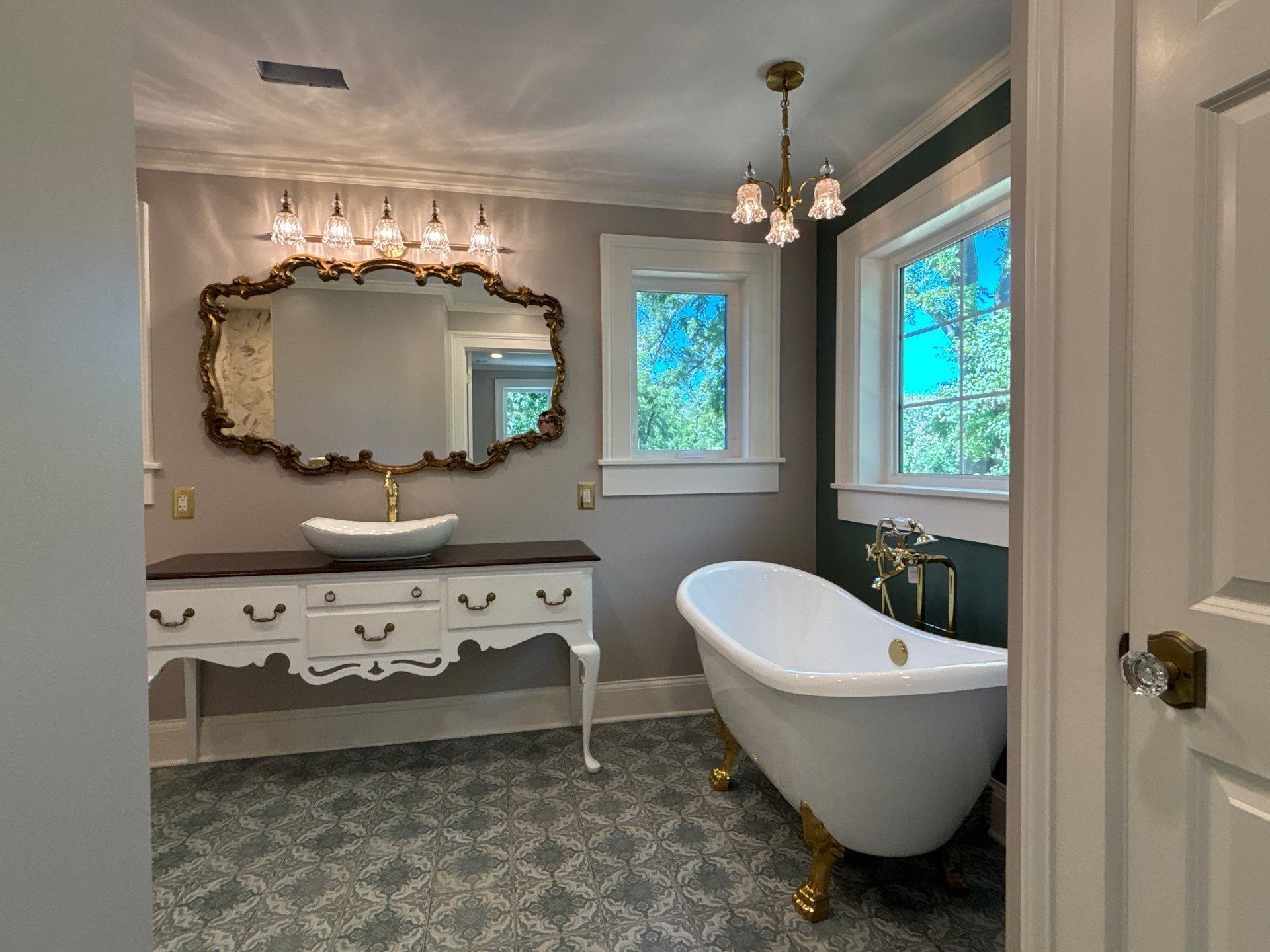 Bathroom with ornate vanity, clawfoot tub, and patterned tile floor.