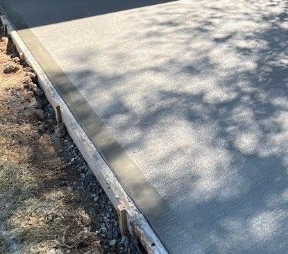 Newly poured concrete slab with wooden formwork and shadows.